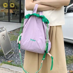 Macro shot of nylon crossbody bag with drawstring closure and green embroidered text