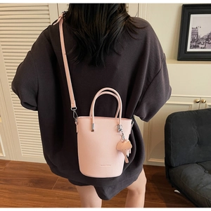 Detailed macro of pink lychee leather bucket bag with cute elephant charm and silver hardware