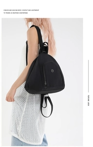 Side view of a black nylon backpack with metal logo on a model with white background