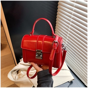 Detail of red matte leather square bag with silver metal buckle and top handle