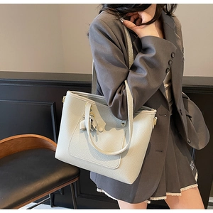 Detailed view of light gray lychee grain leather tote bag worn with a stylish blazer