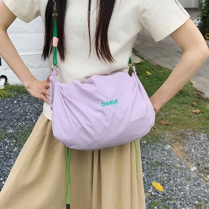 Detail of light purple nylon drawstring bag with green beaut embroidery and colorful strap