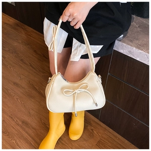 Detailed view of cream-white bow shoulder bag with textured lychee grain leather finish