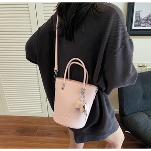 Pink lychee texture bucket bag with bow charm shown in a cozy home setting