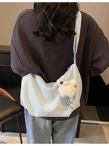 Borsa tote a scacchi azzurra con ciondolo a forma di coniglio di peluche su modella
