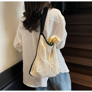 Close-up of cream crochet hobo bag featuring black contrast trim and woven cross pattern