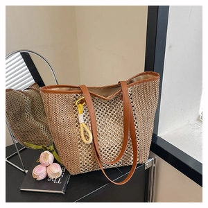 Close-up of woven straw tote bag with brown leather handles and hollow mesh pattern