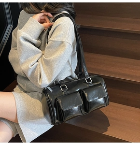Detail of black bowling bag with two front flap pockets and silver hardware on stairs