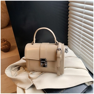 Detail of beige rectangular handbag featuring a silver metal lock and textured leather