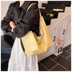 Detail of yellow tote bag showing smooth leather texture and matching small zipper pouch