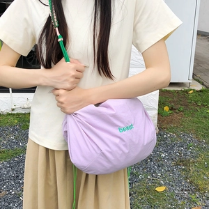 Detail of purple nylon crossbody bag with green beaut embroidery and braided rope strap