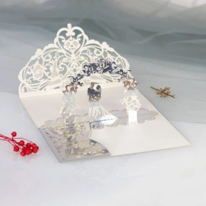 Macro shot of 3D laser-cut wedding invitation with floral arch and couple silhouette