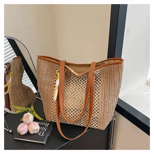 Detail of woven straw tote bag with brown leather handles and decorative yellow charm