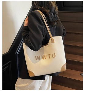 Detail of off-white lychee leather tote bag with brown trim and gold logo on a model