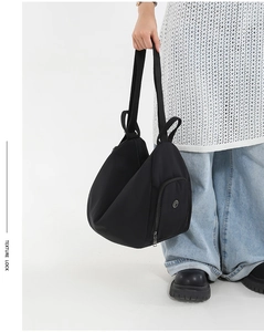 Detail of black nylon tote with adjustable wide shoulder strap and side zipper pocket