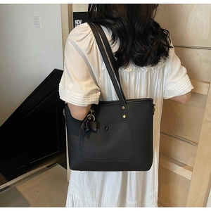 Close-up of black lychee grain tote bag with decorative tassel and gold rivet hardware