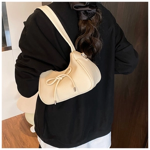 Detailed view of the creamy beige bow knot shoulder bag with textured lychee grain leather