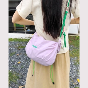 Detail of purple nylon crossbody bag with green embroidery and knotted shoulder strap
