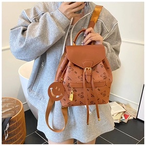 Detailed view of brown lychee leather backpack with bear print and smiley face charm
