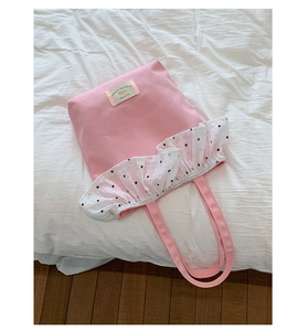 Detailed view of pink canvas tote bag with polka dot lace trim and logo patch