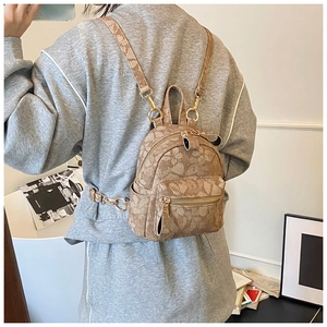 Rear view of model wearing a mini brown backpack with floral embossed texture and gold zippers