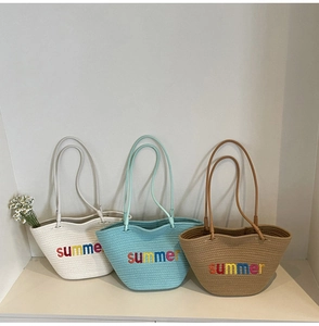Close-up of woven tote bags in beige, mint, and khaki with colorful summer embroidery