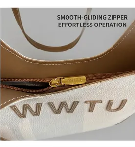Detail of smooth golden zipper and embossed logo on white lychee leather handbag