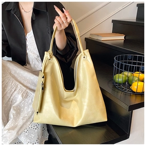 Detail of soft yellow faux leather tote bag with knot handle and matching small pouch accessory