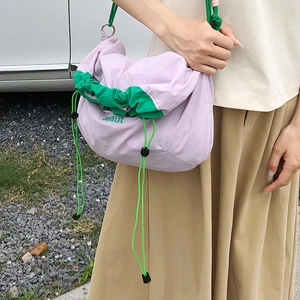 Outdoor shot of the purple nylon drawstring bag with green trim and beaut logo detail