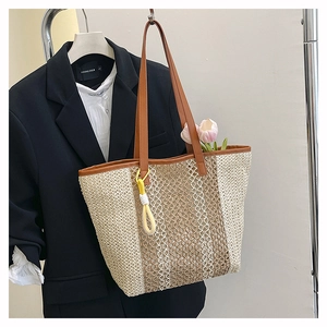 Detail of woven beach tote with brown leather straps and colorful tassel charm