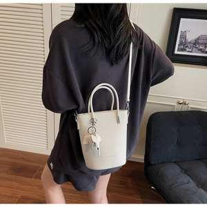 Detailed view of cream white bucket bag with pebble leather texture and elephant charm