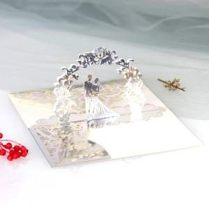 Macro shot of laser-cut 3D pop-up wedding card with silver floral arch and couple silhouette