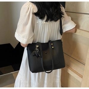 Close-up of black leather tote bag with elegant elephant charm and gold hardware detail