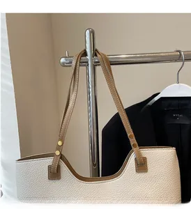 Detail of white lychee leather tote bag with brown straps and metal rivet reinforcement