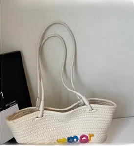 Close-up of woven straw tote bag featuring colorful summer embroidery and sturdy handles
