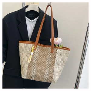 Detail of woven straw beach tote with leather handles and yellow rope tassel decoration