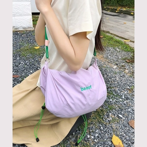 Detail of light purple nylon crossbody bag featuring lime green drawstrings and embroidery