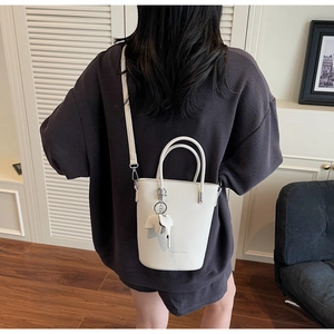Modern white bucket bag with pebble leather texture and a cute elephant charm charm