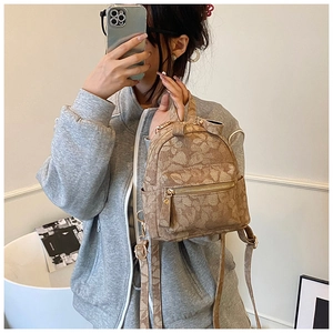 Detail of vintage floral print canvas backpack featuring multiple zipper compartments