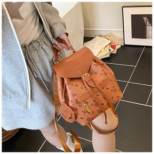 Detailed view of brown leather backpack with bear print and stylish smiley charm pendant