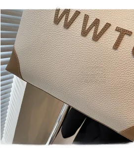 Detail of lychee textured cream tote bag with brown leather embroidery and corner patches