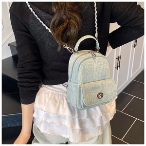 Detailed side view of a light blue denim mini backpack with silver metal chain straps