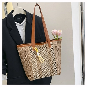 Detail of woven straw tote bag with brown leather handles and yellow knot pendant
