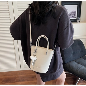 Detail of off-white lychee texture bucket bag with cute elephant charm and thin strap