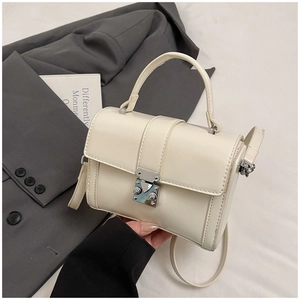 Detail of a creamy white mini square bag with silver metal buckle and top handle