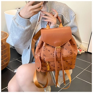 Close-up of brown leather backpack with bear prints and a smiley face pendant