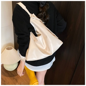 Detail view of cream white large tote bag with soft faux leather texture on model shoulder