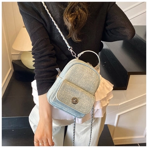 Close-up of light blue denim mini backpack with silver chain strap and metal swivel lock