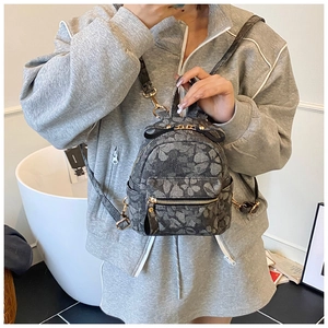 Detailed close-up of a mini floral backpack with a black bow and gold zipper hardware