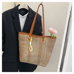Detail view of woven beach tote with brown leather handles and yellow round pendant charm